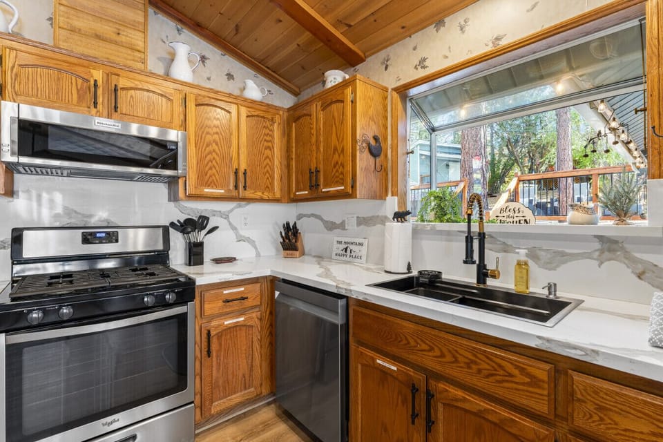 Fully equipped kitchen w/ stainless steel appliances, wood cabinetry & window over the sink.