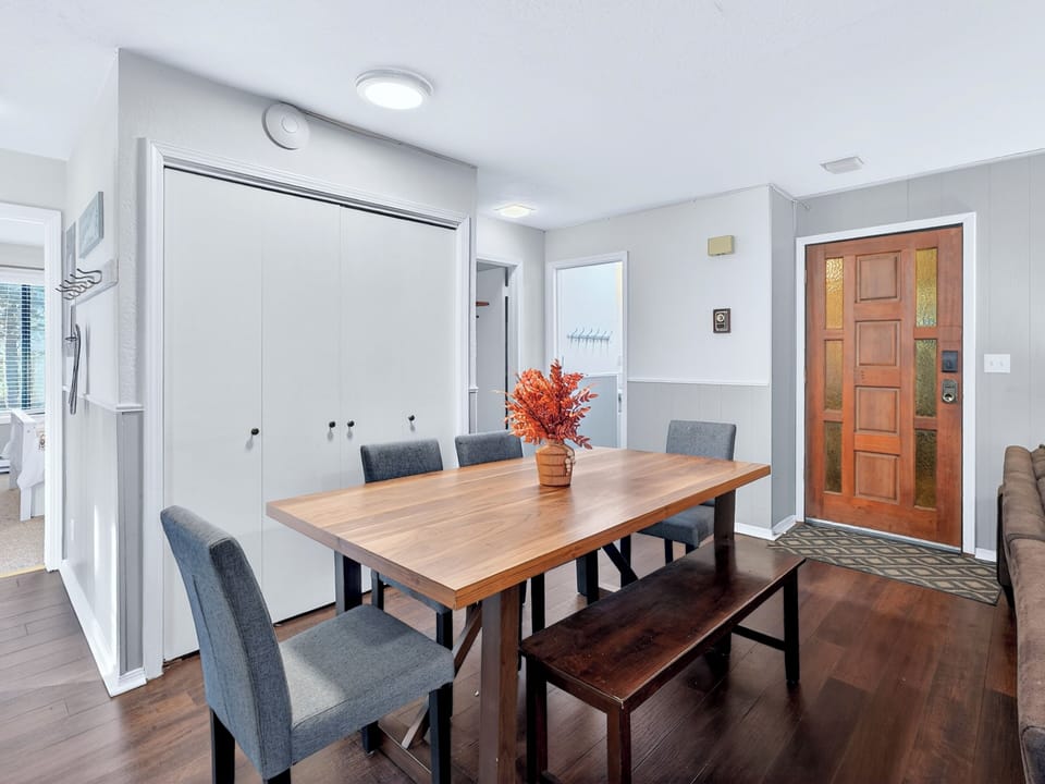 Bright dining nook with wood table, bench seating, and stylish entry.