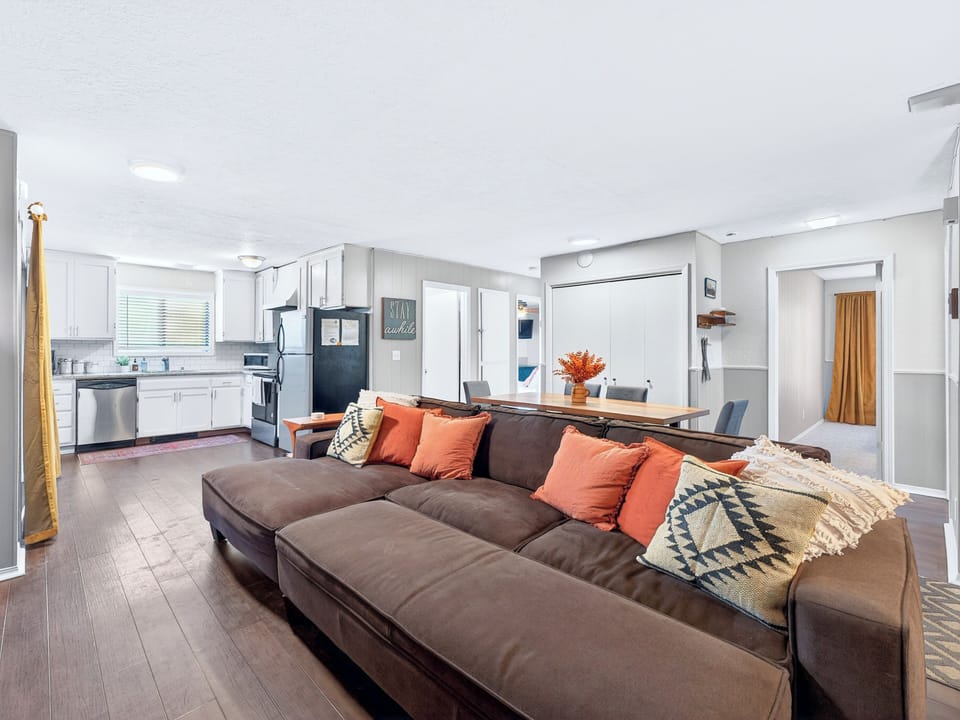 Bright open-plan lounge with plush sectional, dining area & sleek kitchen.