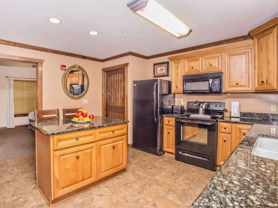 Another view of the kitchen showing the island, oven, and refrigerator in open layout.