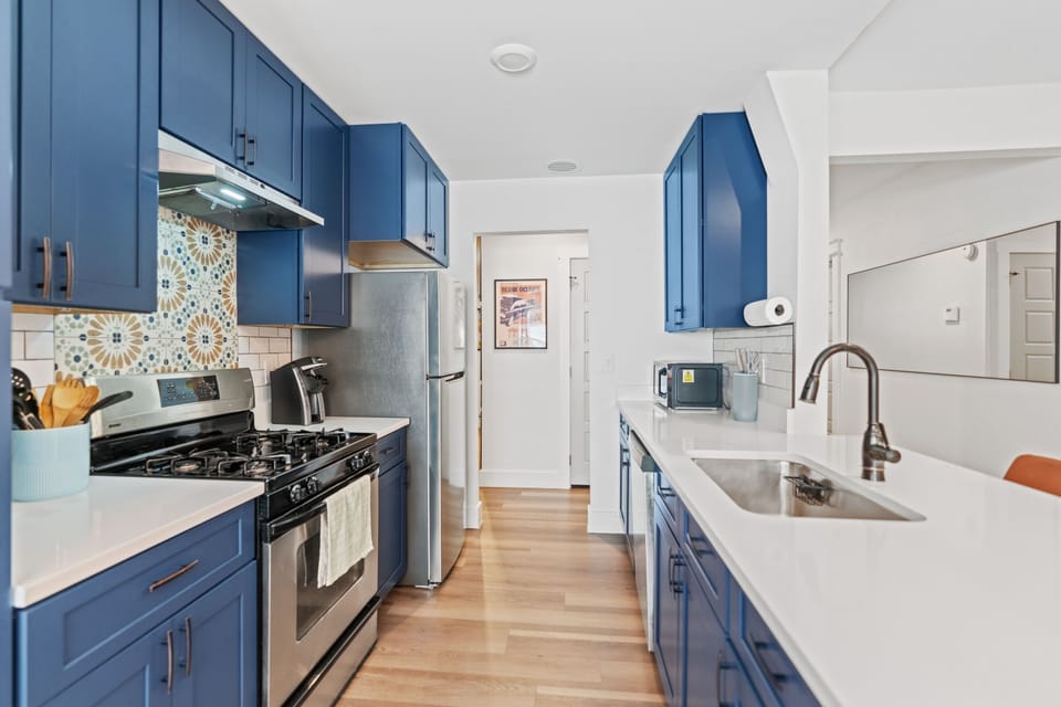 Whip up meals in this modern kitchen with vibrant blue cabinetry, then explore nearby eats like Aviator Pizza, enjoy craft brews at Lustre Pearl South, or unwind at Mary Moore Searight Park.