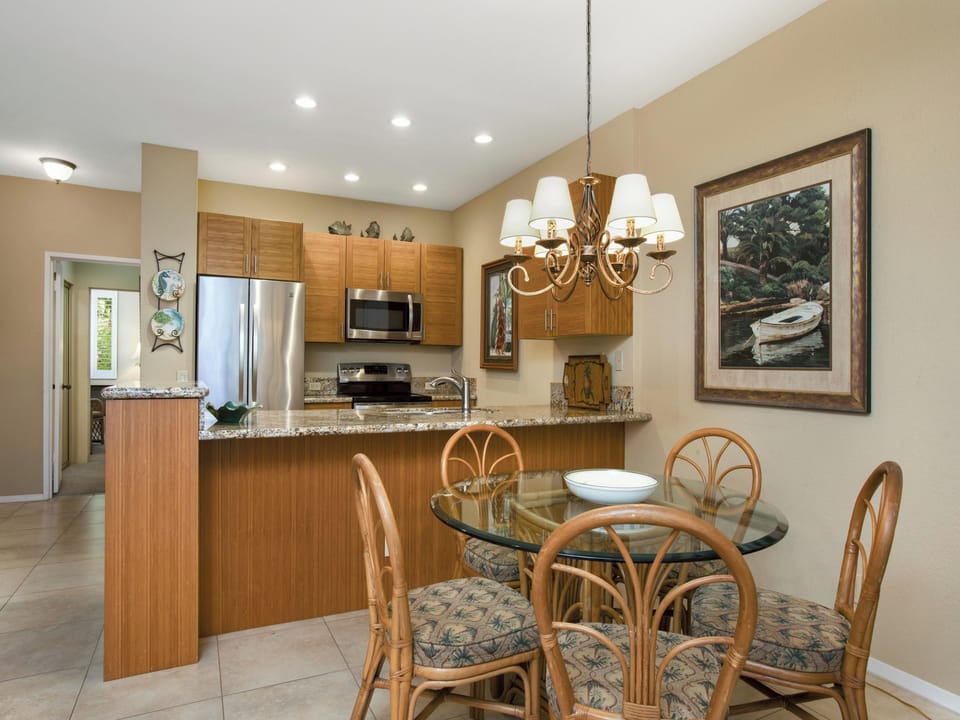 Step into your open kitchen and dining area, where warm wood tones and granite countertops create an inviting space for preparing meals and gathering with loved ones around the glass-top table.