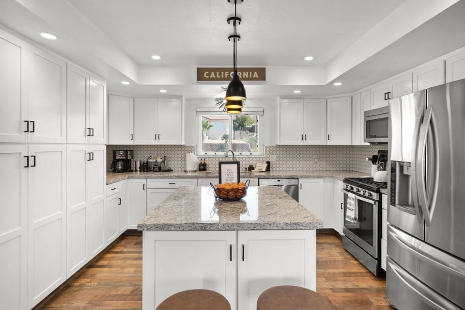 Stainless steel gleams as sunlight dances across counters—this kitchen invites creativity and connection with every meal.