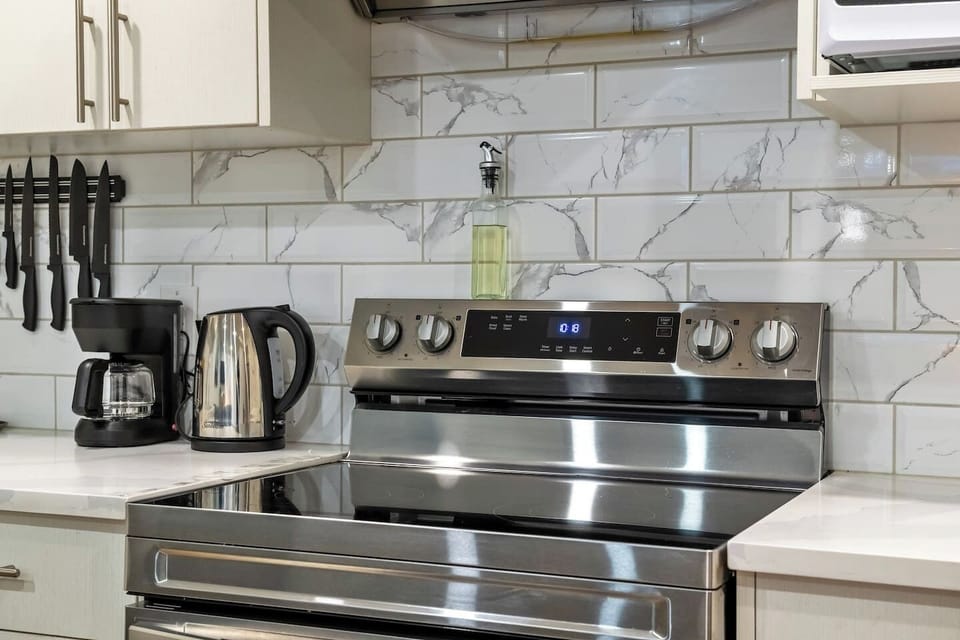 Well-appointed kitchen featuring stainless steel range, coffee makers, and marble backsplash