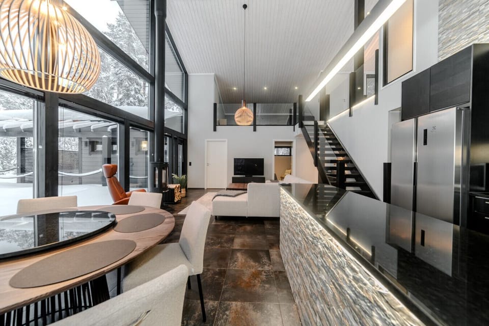 The open-plan living area is the heart of the home. It includes a modern lounge with large sofas, a flat-screen TV, and beautiful views of the surrounding nature. The stylish Nordic interior blends wood, light, and space to create a calming atmosphere – p