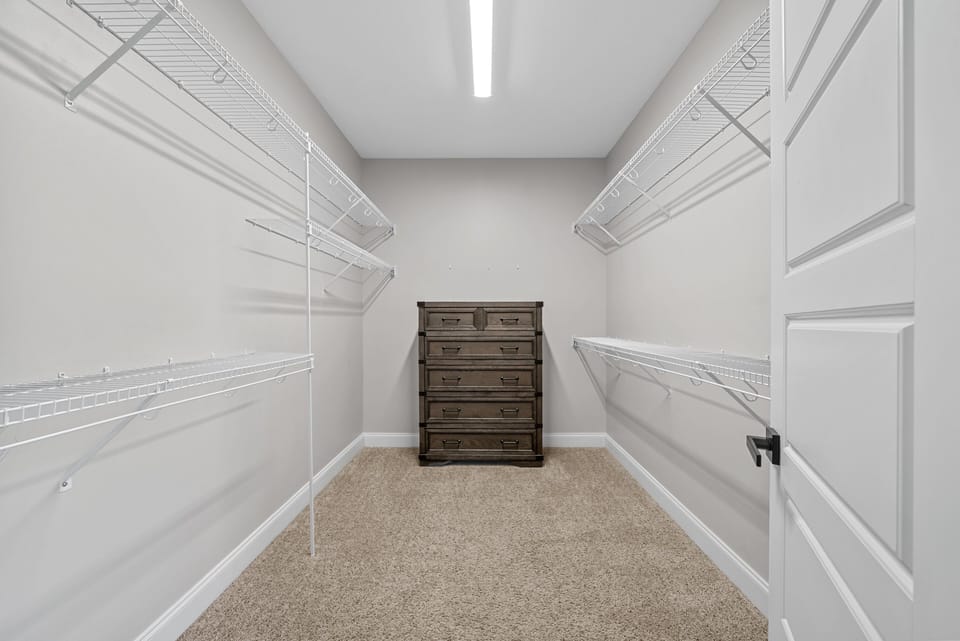 Expansive walk-in closet with built-in shelving and carpeted flooring