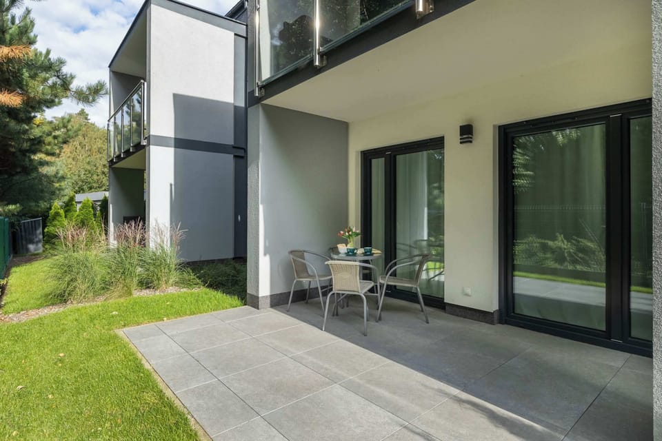 The exterior of the building with a covered terrace area and seating. The modern design blends with the surrounding greenery.