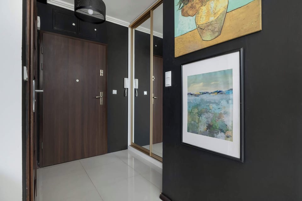 The spacious hallway with decorative paintings and dark doors welcomes guests into the elegant interior of the apartment.