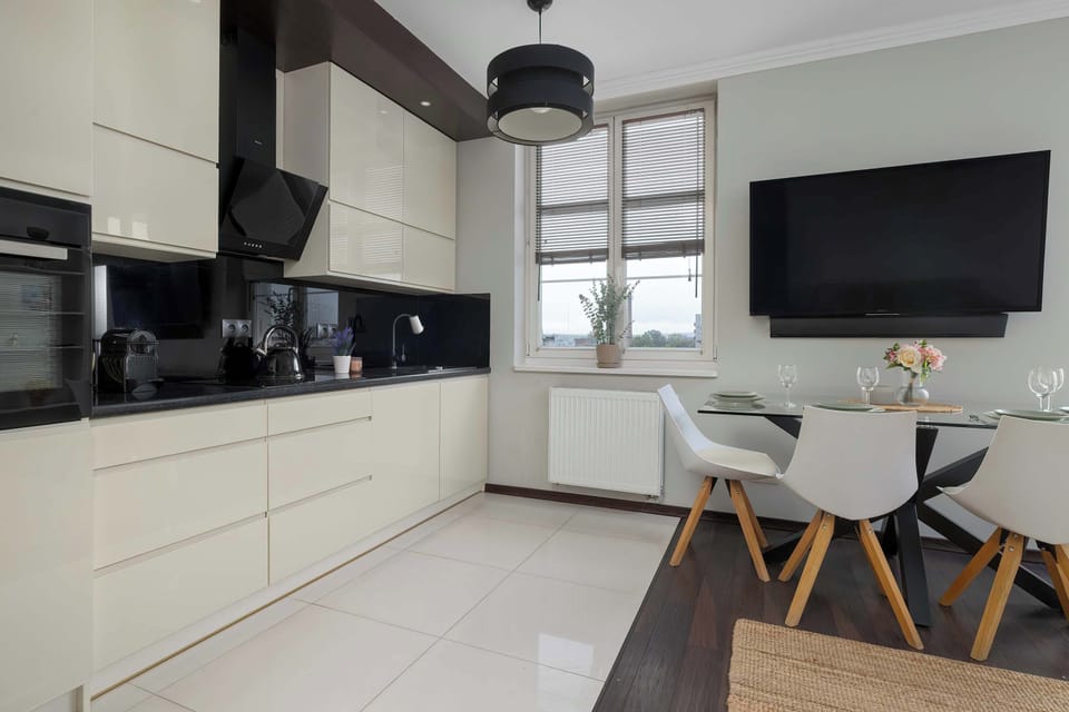 The kitchen with light cabinetry and a large dining table by the window offers a convenient space for both cooking and shared meals.