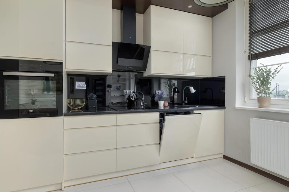 The minimalist-style kitchen with glossy white cabinetry and black accents provides a space that inspires culinary creativity.
