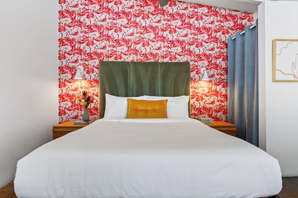 The Queen Studio features a plush queen bed, TV, ceiling fan, and vibrant Palm Springs style.