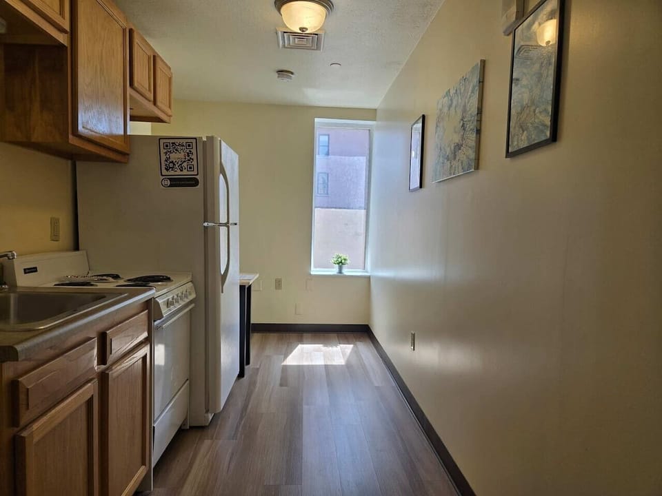 Bright galley kitchen w/ full-size fridge, stove & warm wood flooring throughout.