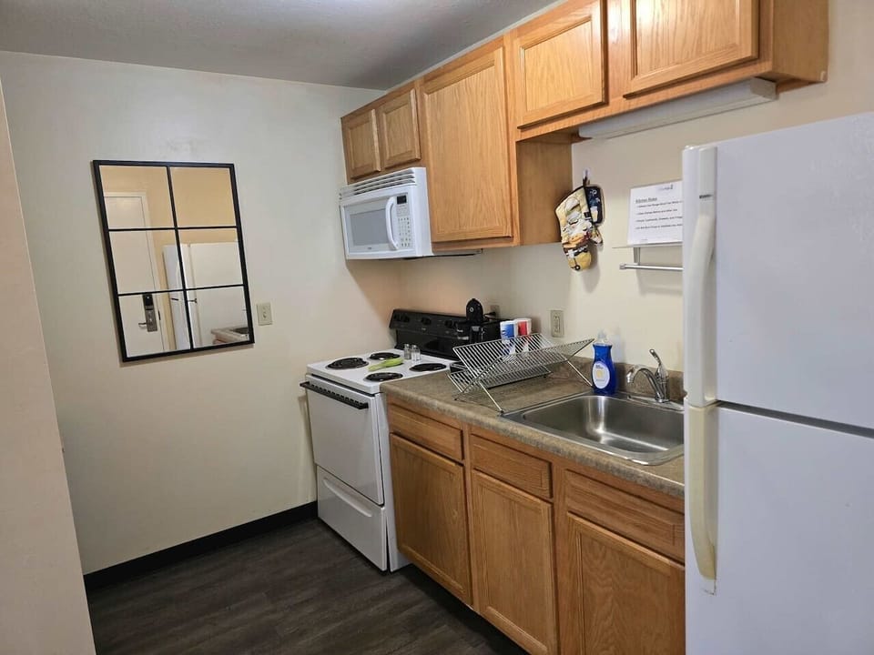 Fully equipped kitchen w/ white appliances & wood cabinetry, ready for easy home-cooked meals.