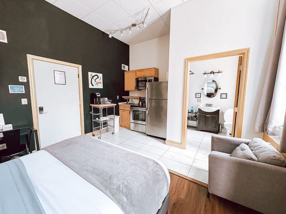 Sun-filled corner w/ oversized mirror & doorway opening onto the kitchenette—airy and open.