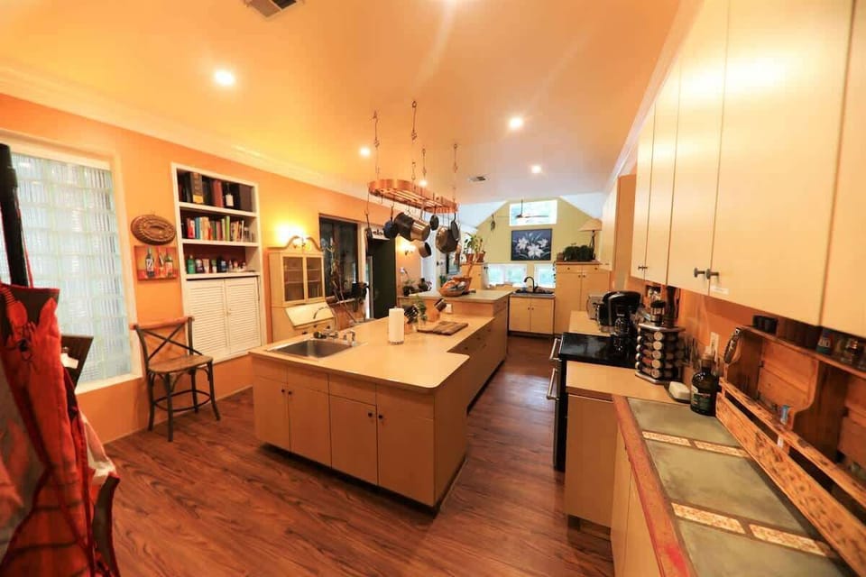 Kithen longways again, high-vaulted ceiling in the den, 12' in main kitchen, with copper pot rack, Top of the line and impossinle to find Griswald cast iron skillets and quality cookware