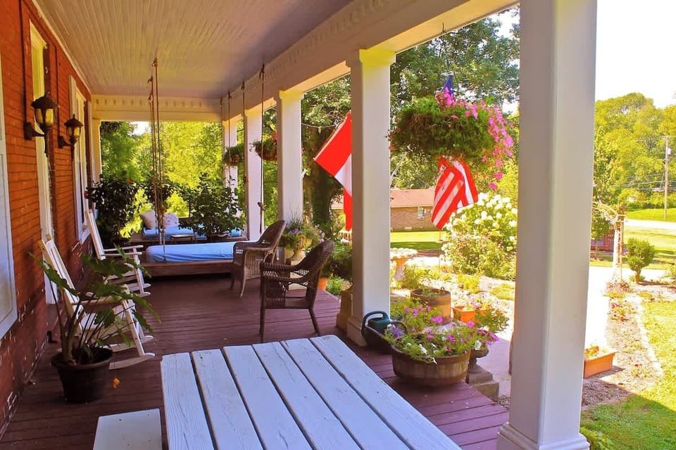 Western facing front porch on a warm, sunny summer morning with double swinging day beds