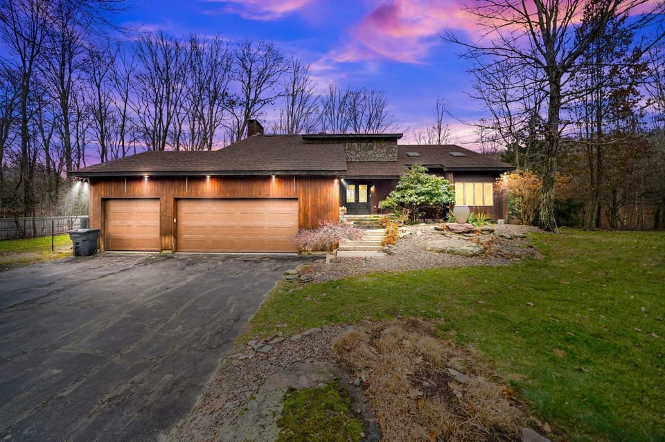 Modern mountain-style exterior with elegant lighting and a spacious driveway.