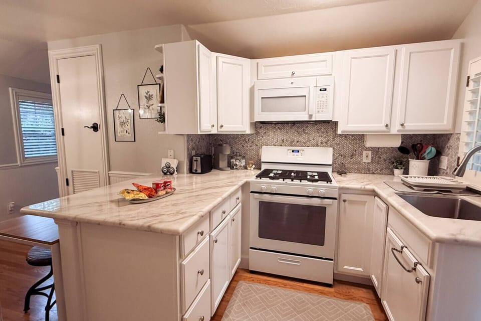 The kitchen fully equipped, featuring clean white cabinetry, generous cabinet space, and modern appliances. The layout is both functional and inviting - with everything you need within easy reach
