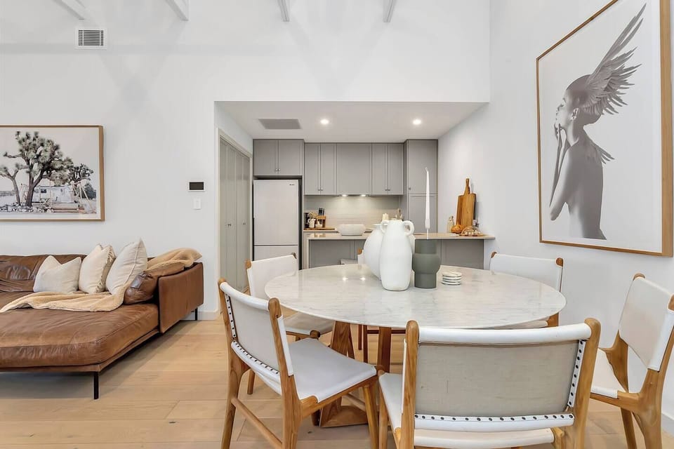 Gather around the dining table beneath statement artwork, perfect for shared meals and conversation after a day by the beach.