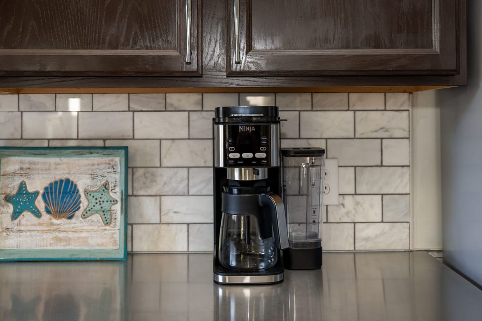Wake up to fresh coffee brewing in your fully equipped kitchen, complete with modern appliances and charming coastal touches.