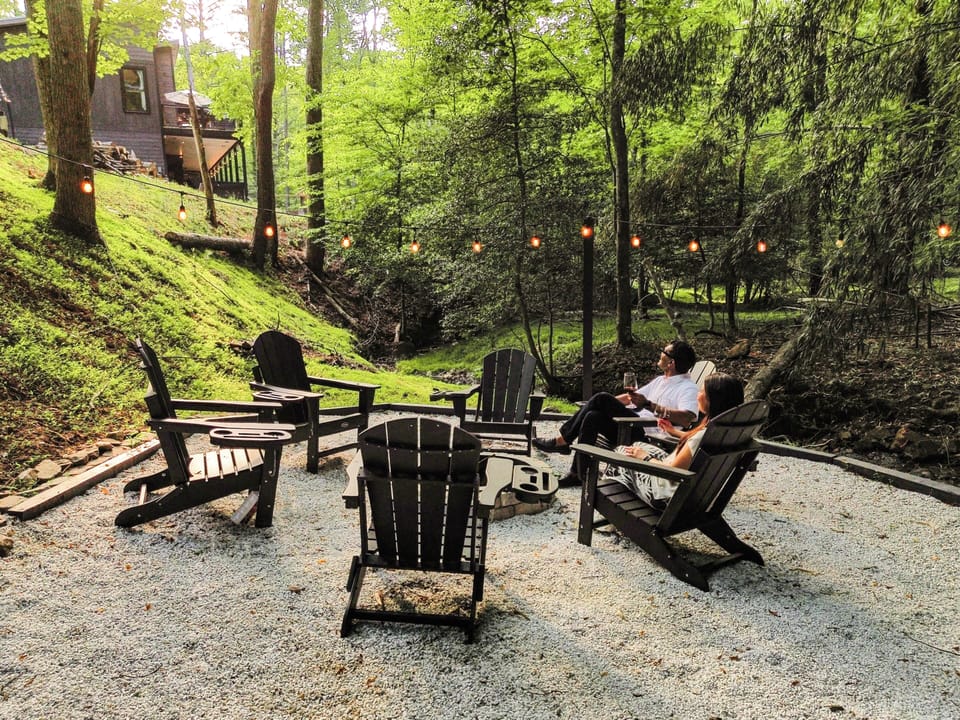 Cozy forest fire pit with string lights and Adirondack seating
