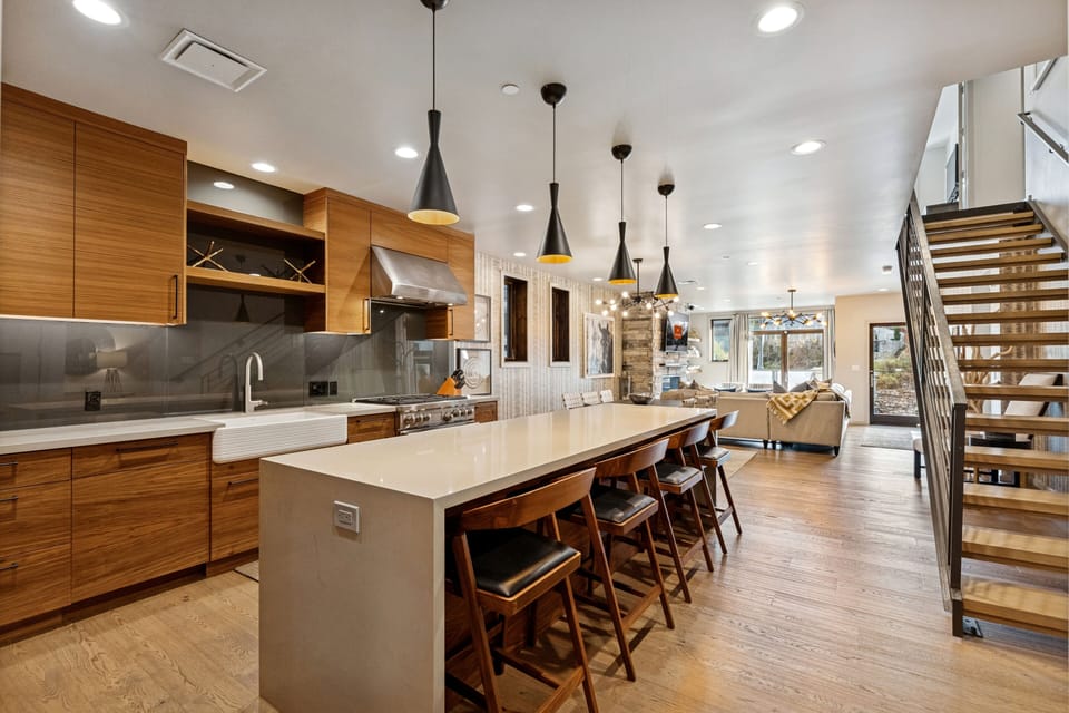 Spacious kitchen with wood cabinetry, large island, and modern pendant lighting