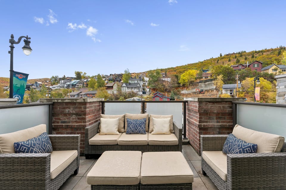 Rooftop terrace with cushioned loungers, mountain views, and brick privacy walls