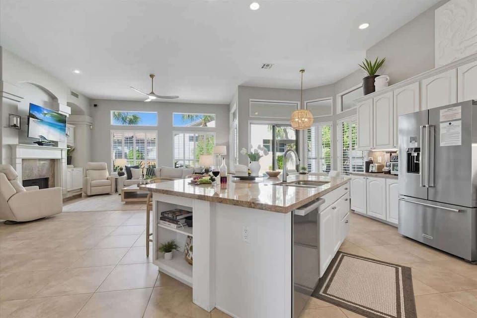 The kitchen showcases granite countertops, crisp white cabinets, stainless steel appliances, and a spacious island with breakfast bar seating for three.