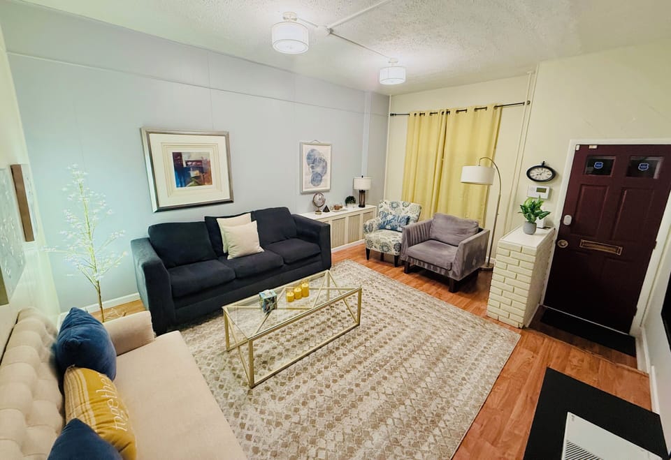The living room features seatings for your family, a smart TV, and sunlight