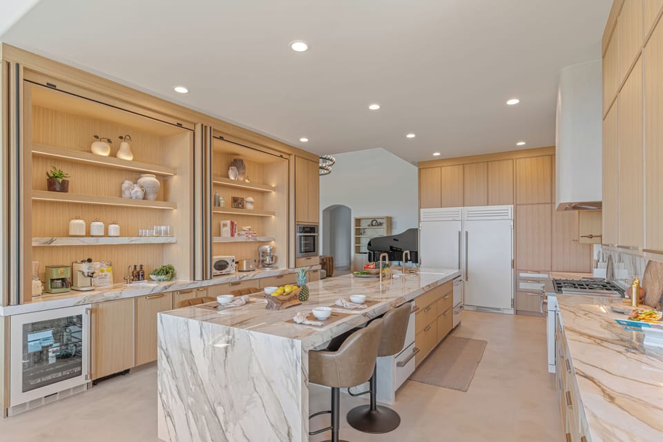 Large waterfall island, high-end appliances, and stunning stone countertops and backsplash.