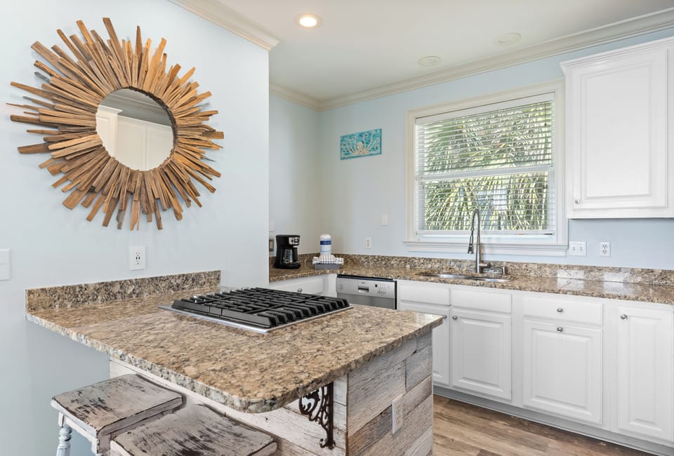 Kitchen with a bright breakfast area featuring a stylish sunburst mirror and warm tones.