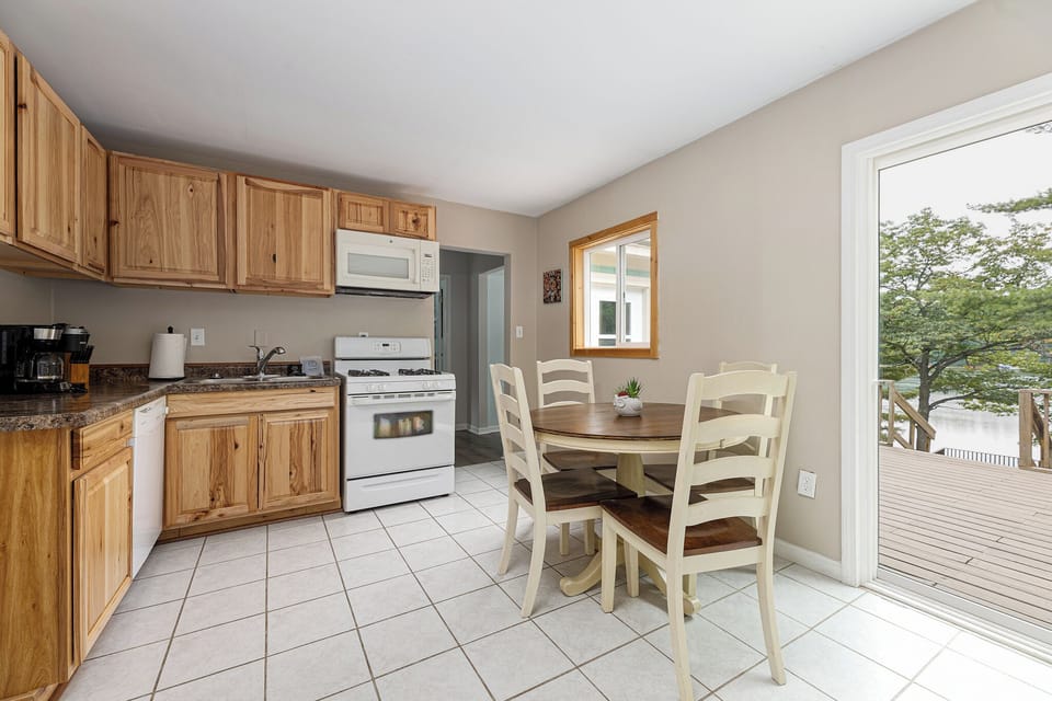 Bright kitchen & dining area w/ wood cabinets and sliding door leading to the deck