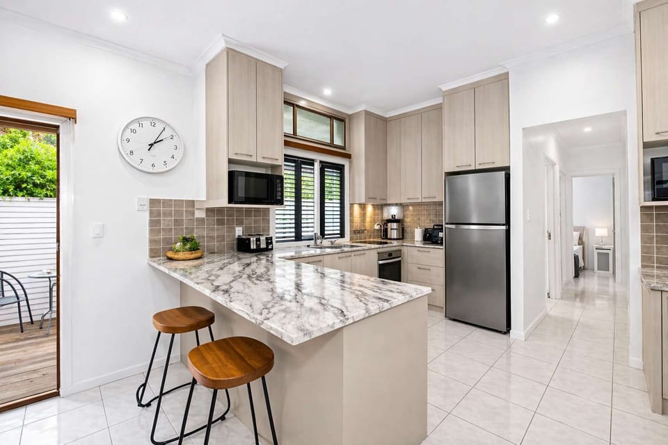 Bright and modern kitchen featuring a stylish island bench, quality appliances, and seamless indoor-outdoor flow to a private patio.