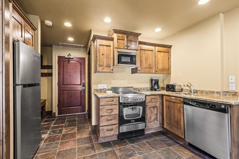Your fully equipped kitchen awaits with warm wood cabinets, granite countertops, and stainless steel appliances.
