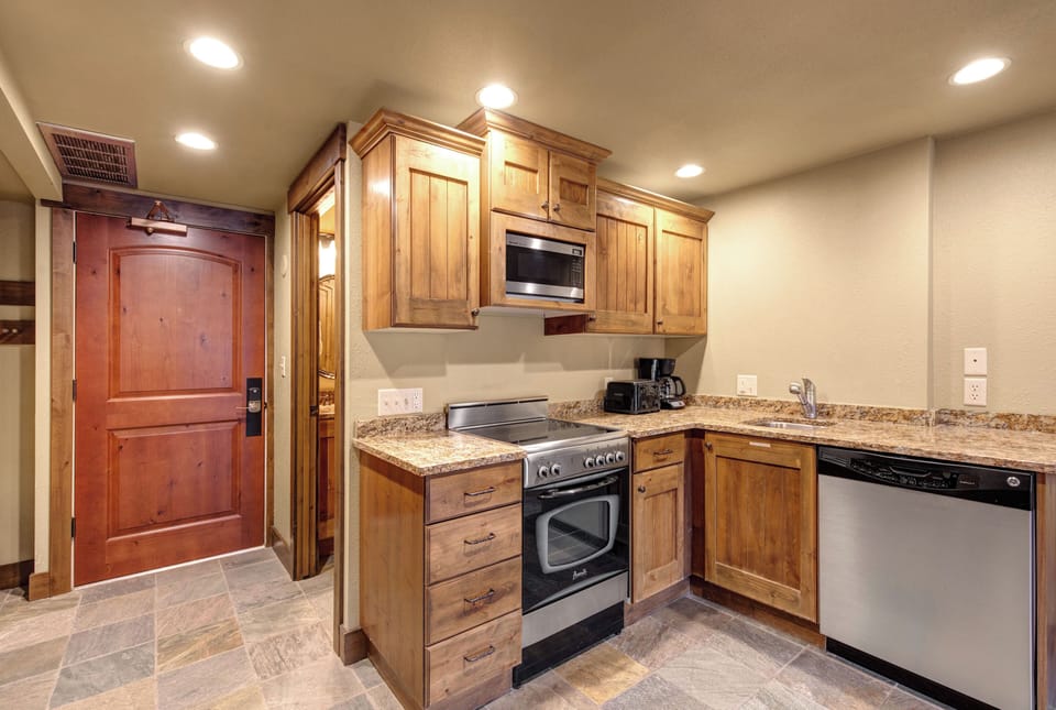 Your fully equipped kitchen awaits with warm wood cabinets, granite countertops, and modern stainless steel appliances.
