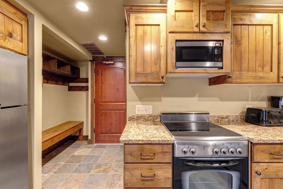Step into your mountain retreat kitchen where rustic wood cabinets and granite counters create the perfect space.
