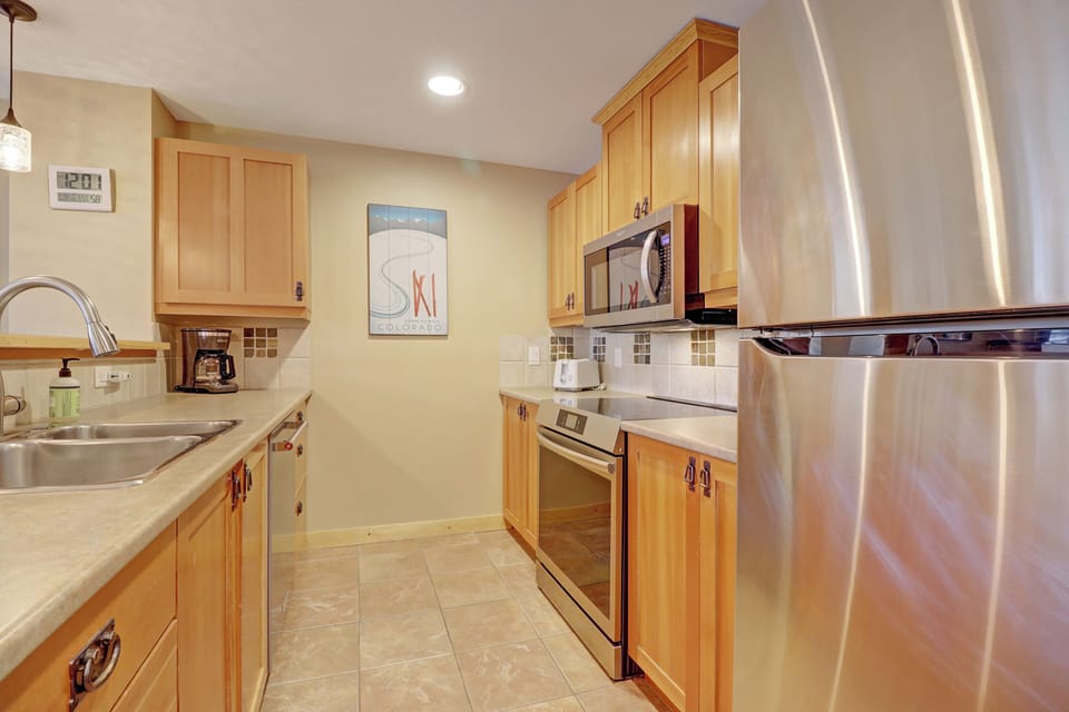 Well-equipped kitchen featuring stainless steel appliances, warm wood cabinetry, and ample counter space. Ideal for preparing hearty mountain meals after a day of skiing or hiking.