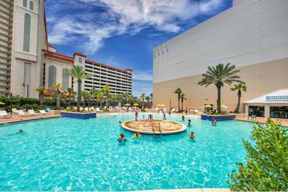 Relax at the resort’s signature tropical pool surrounded by palms, loungers, and sunshine.
