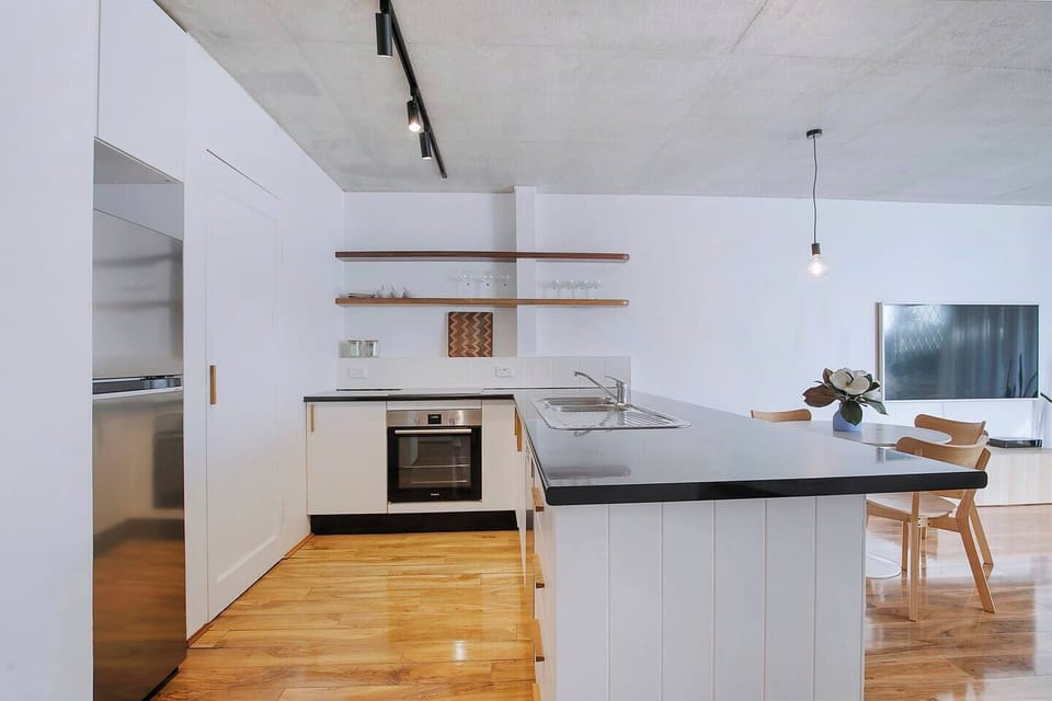 The kitchen’s sleek black benchtops, open timber shelving, and stainless-steel appliances create a stylish space to prepare fresh local produce or your morning coffee.