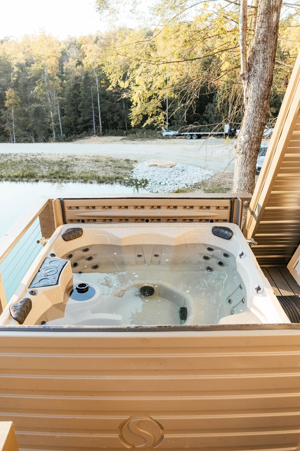 Private hot tub on the deck with peaceful pond and forest views—perfect for relaxing after a day of adventure.