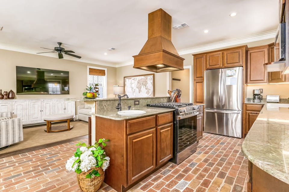 Gourmet kitchen with gas range, copper hood, granite counters, and Chicago brick floors