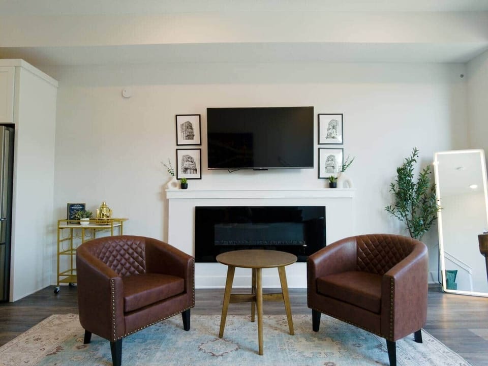 55-inch Amazon Fire TV flanked by local artist Guardians of the Bridge prints. Club chairs, an indoor fireplace, a bar cart and an LED standing mirror in the Living room.