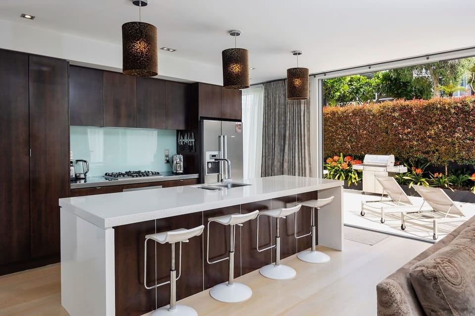Fully equipped kitchen with sliding doors leading out to a sunny terrace with BBQ and sun loungers