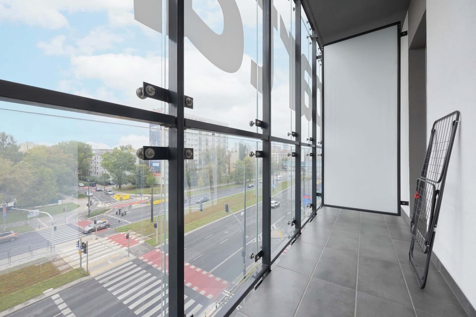 The glass-enclosed balcony overlooking the city is a perfect spot to enjoy your morning coffee and watch the lively streets below.