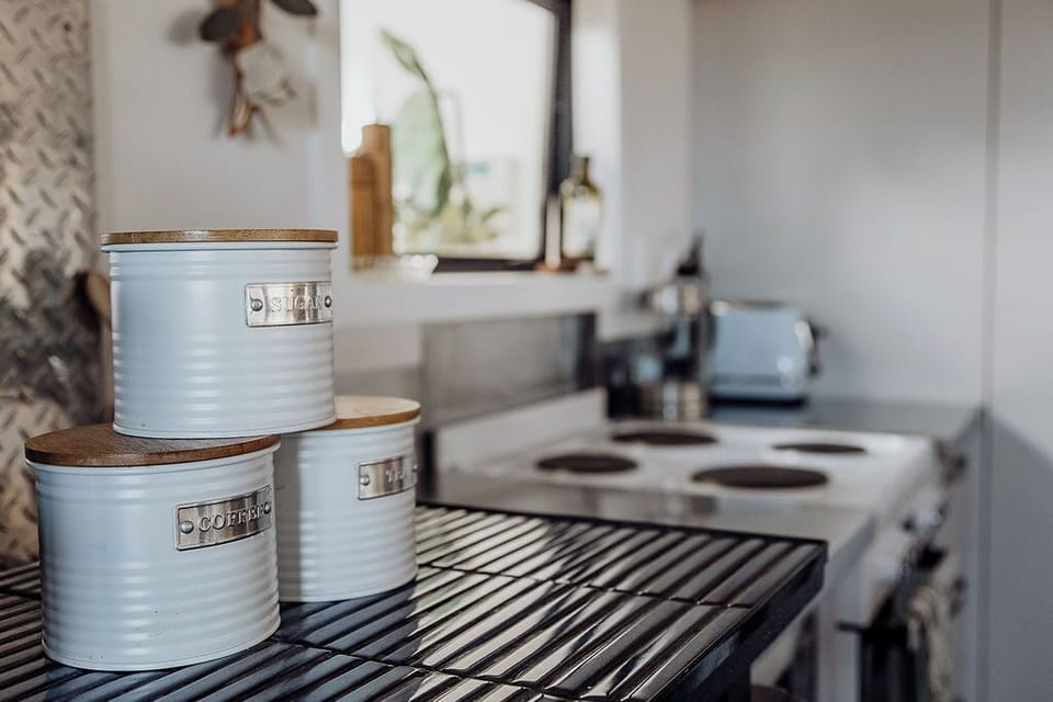 Even the essentials are beautiful. Warm wood, vintage tins, and a stovetop ready for your favourite comfort meal.
