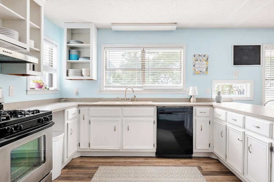 Bright and spacious kitchen with ample counter space, open shelving, double oven, and a breakfast bar fully equipped for easy meal prep and family gatherings.