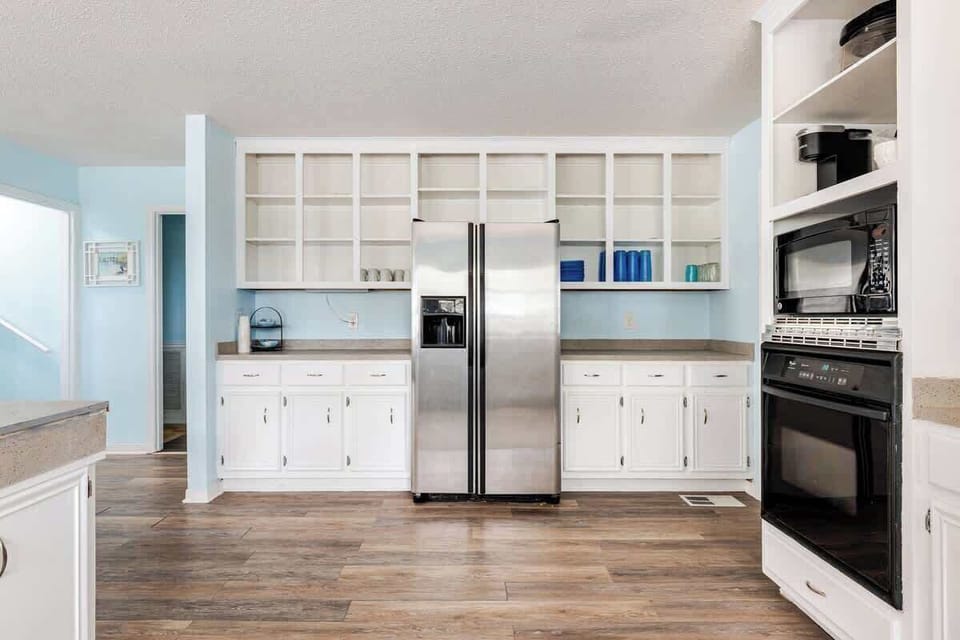 Bright and spacious kitchen with ample counter space, open shelving, double oven, and a breakfast bar fully equipped for easy meal prep and family gatherings.