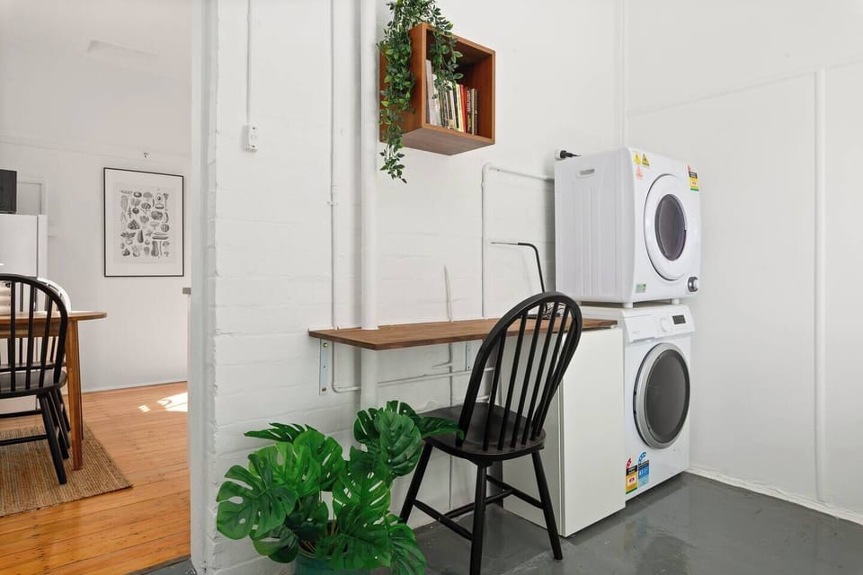 The second bedroom doubles as a multipurpose space with a desk for remote work and laundry facilities tucked neatly alongside.