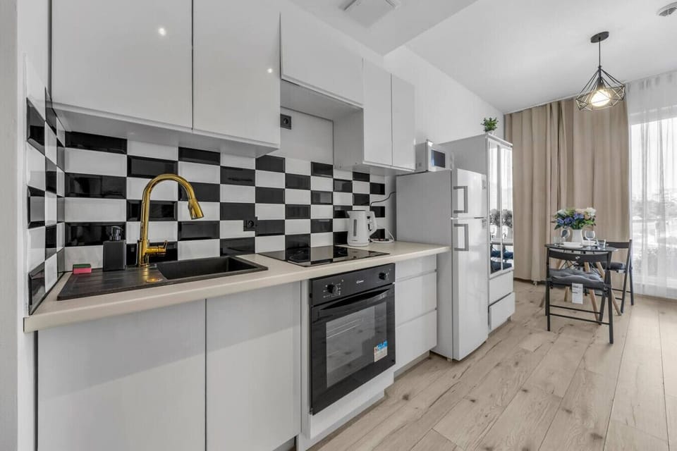 Modern Kitchen Area – Fully equipped with a stove, oven, fridge, microwave, and stylish black-and-white backsplash for your cooking convenience | Book Now with RENTUJEMY.COM