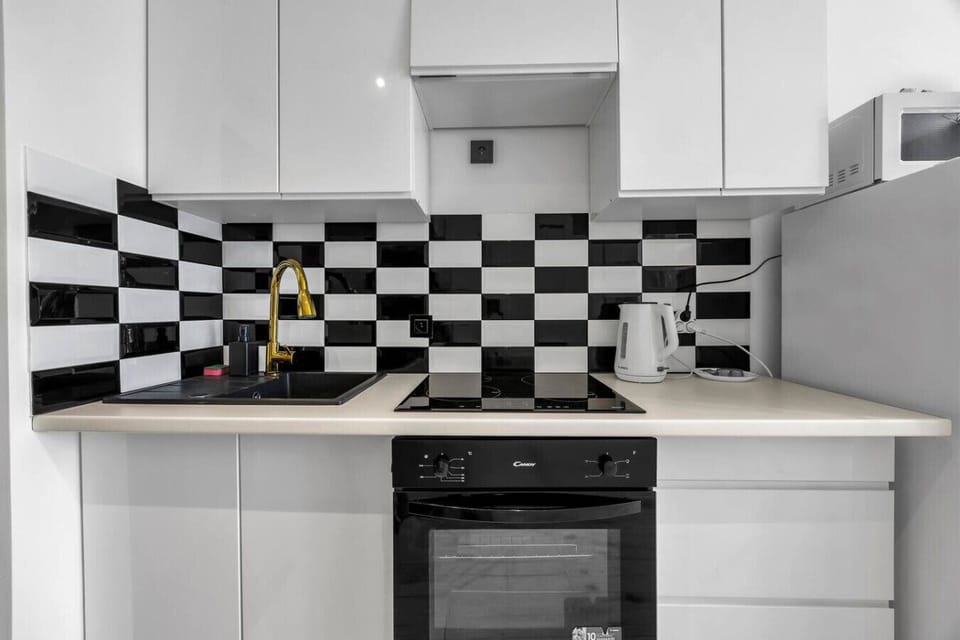 Modern Kitchen Area – Fully equipped with a stove, oven, fridge, microwave, and stylish black-and-white backsplash for your cooking convenience | Book Now with RENTUJEMY.COM